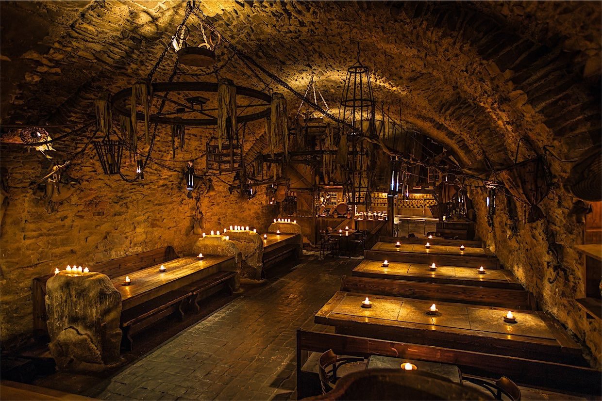 Inside the medieval restaurant, the tables are dotted with candles and there is a large chandelier hanging from the ceiling