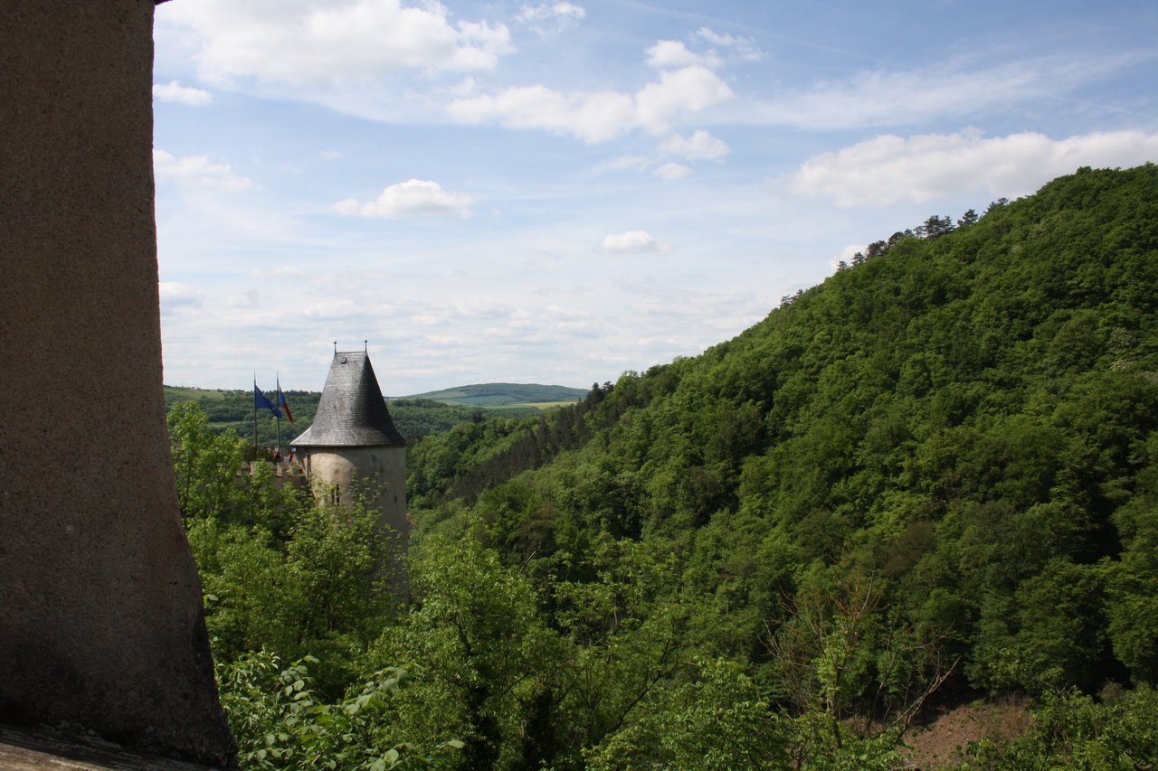 View of the castle tower, with the flags of Europe and the Czech Republic on the side, and a forest in the background