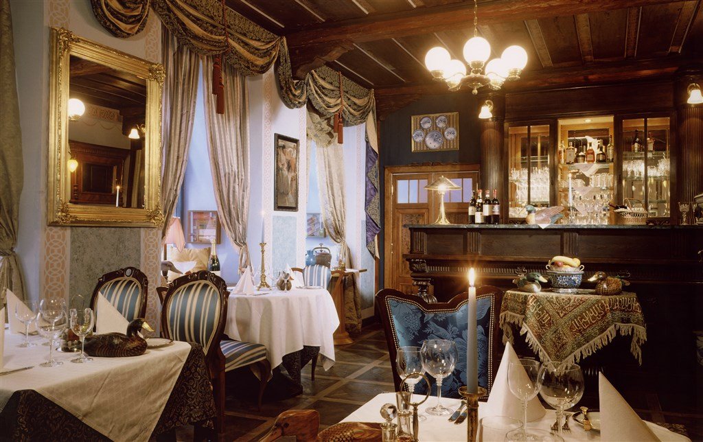 A room filled with restaurant tables, candles, and a chandelier in the center