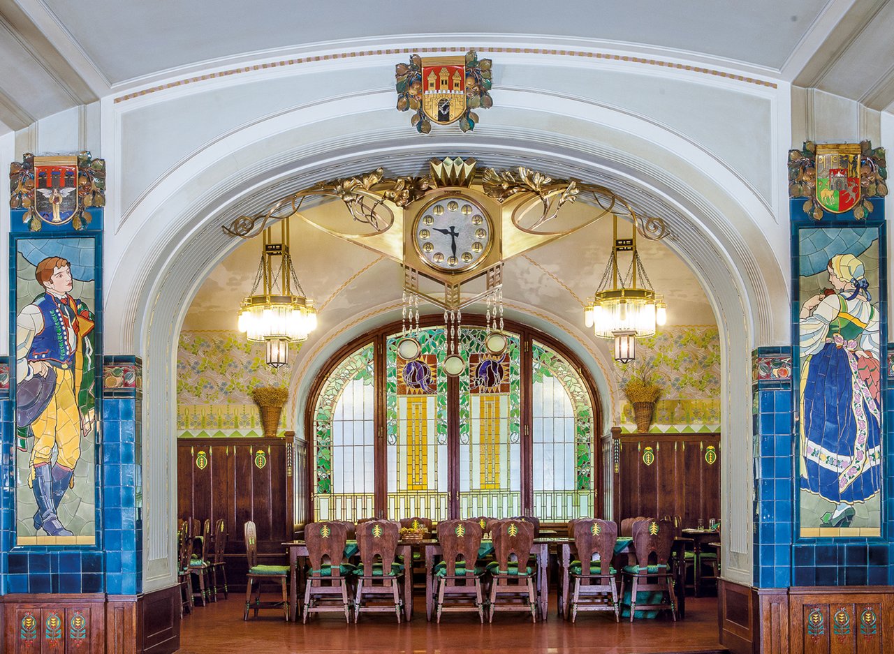 A room with a mosaic of a man on the left post and a woman on the right one
