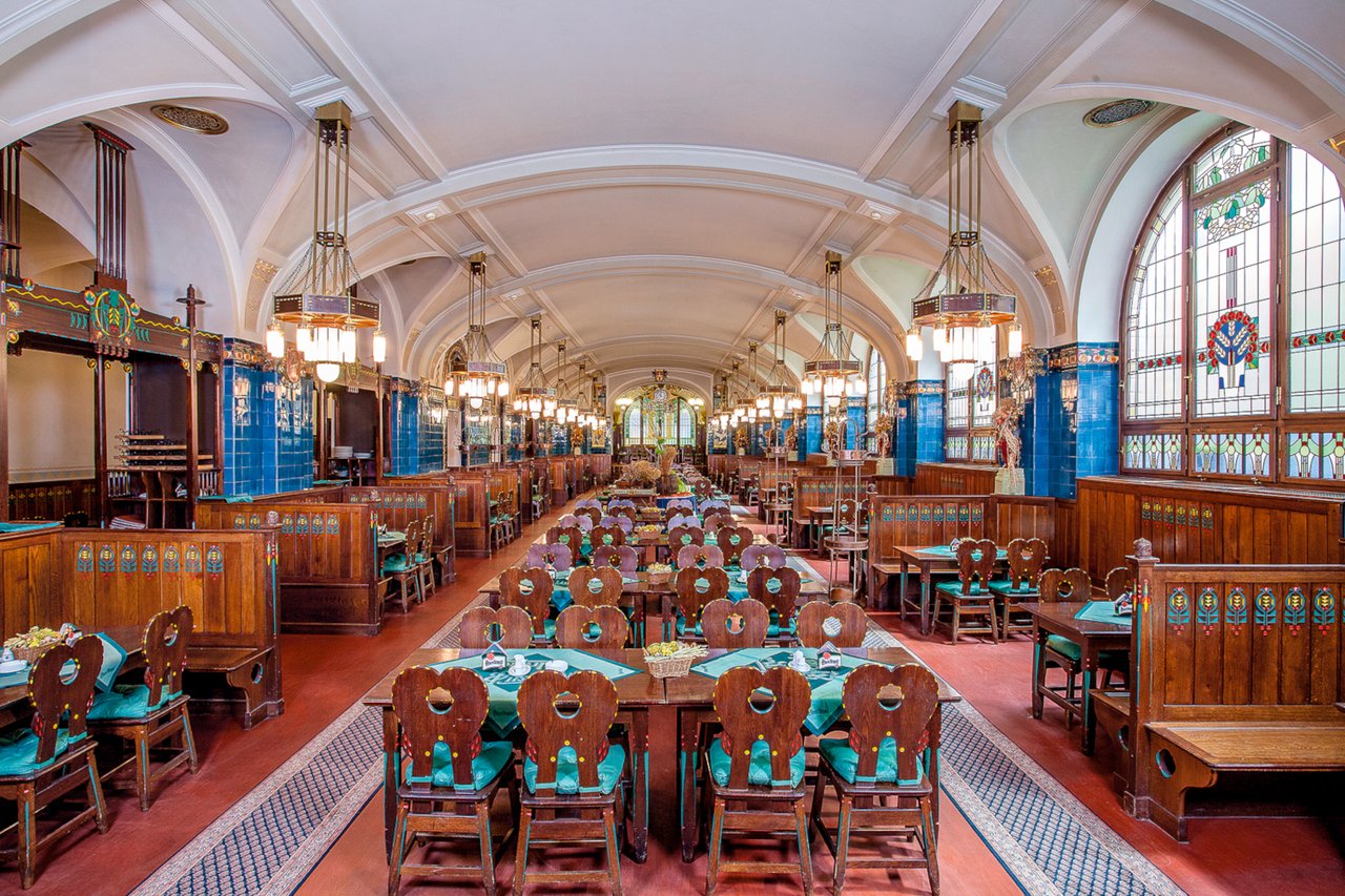 The interior of a brasserie with many tables and lots of color, featuring a vaulted ceiling