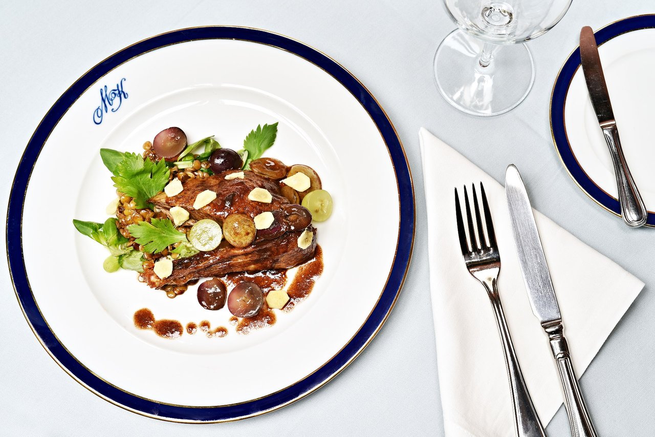 Meat dishes on a blue-and-white plate with silver-gray cutlery and a glass