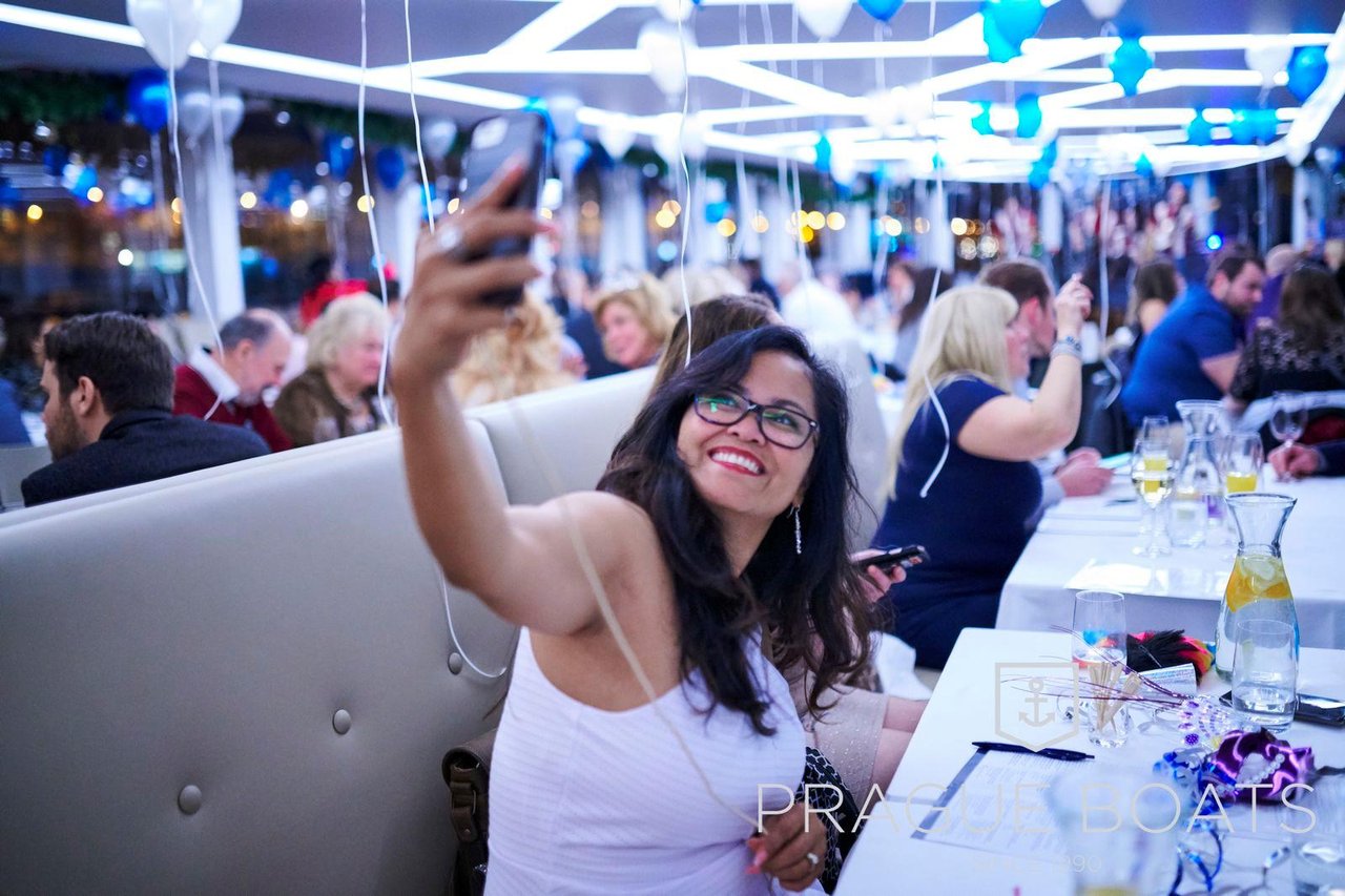 A woman taking a selfie in a crowd of people sitting on chairs