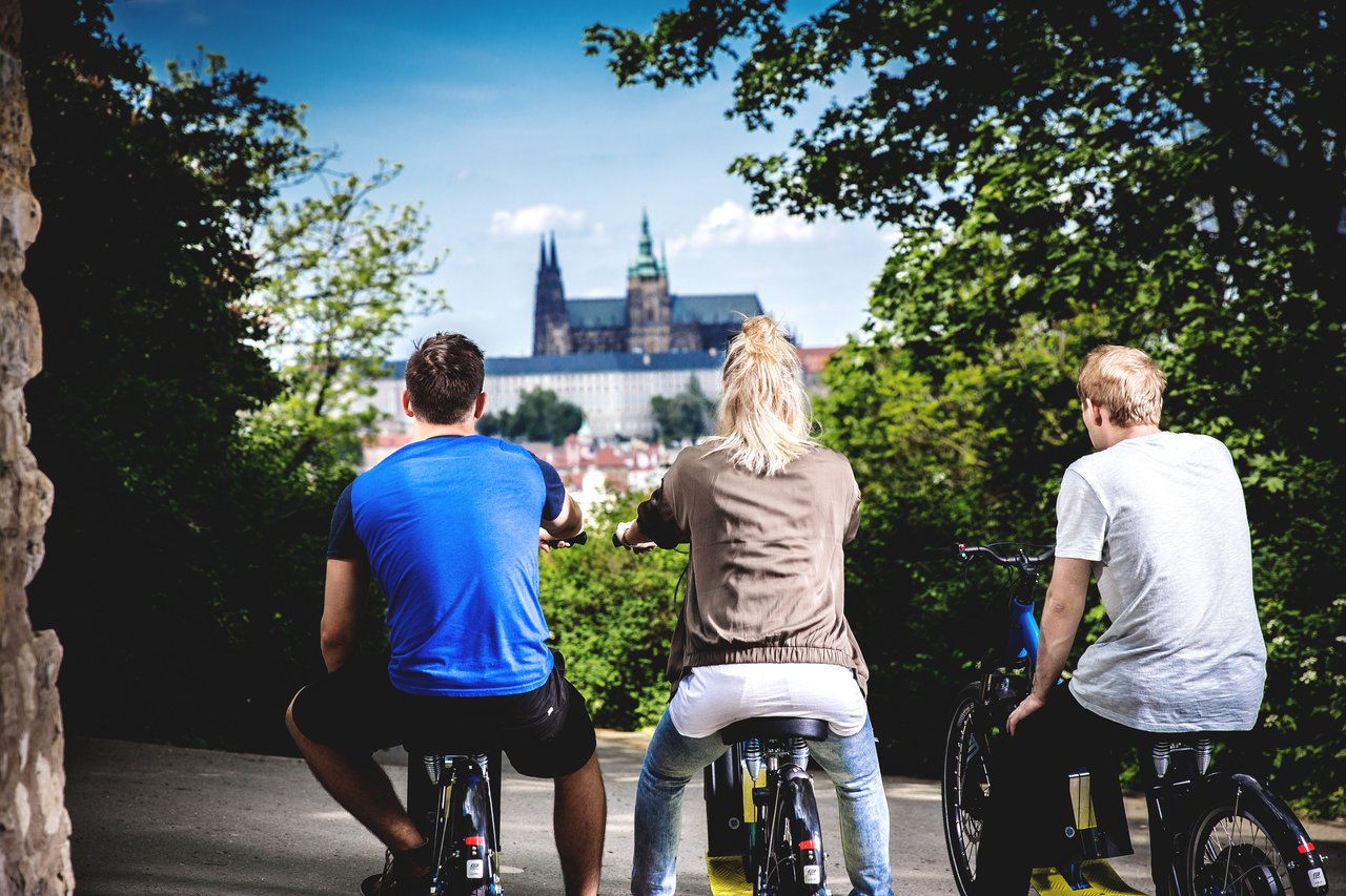 Three people seen from behind on electric Scooter , admiring the view of the castle