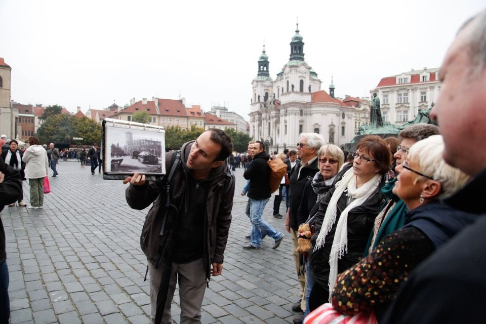 A guide shows a historical black and white photograph to a group of attentive people.