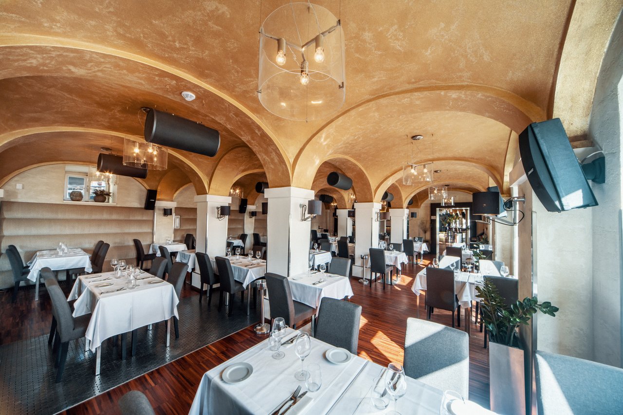 A dining room with a vaulted ceiling and several speakers mounted in various locations
