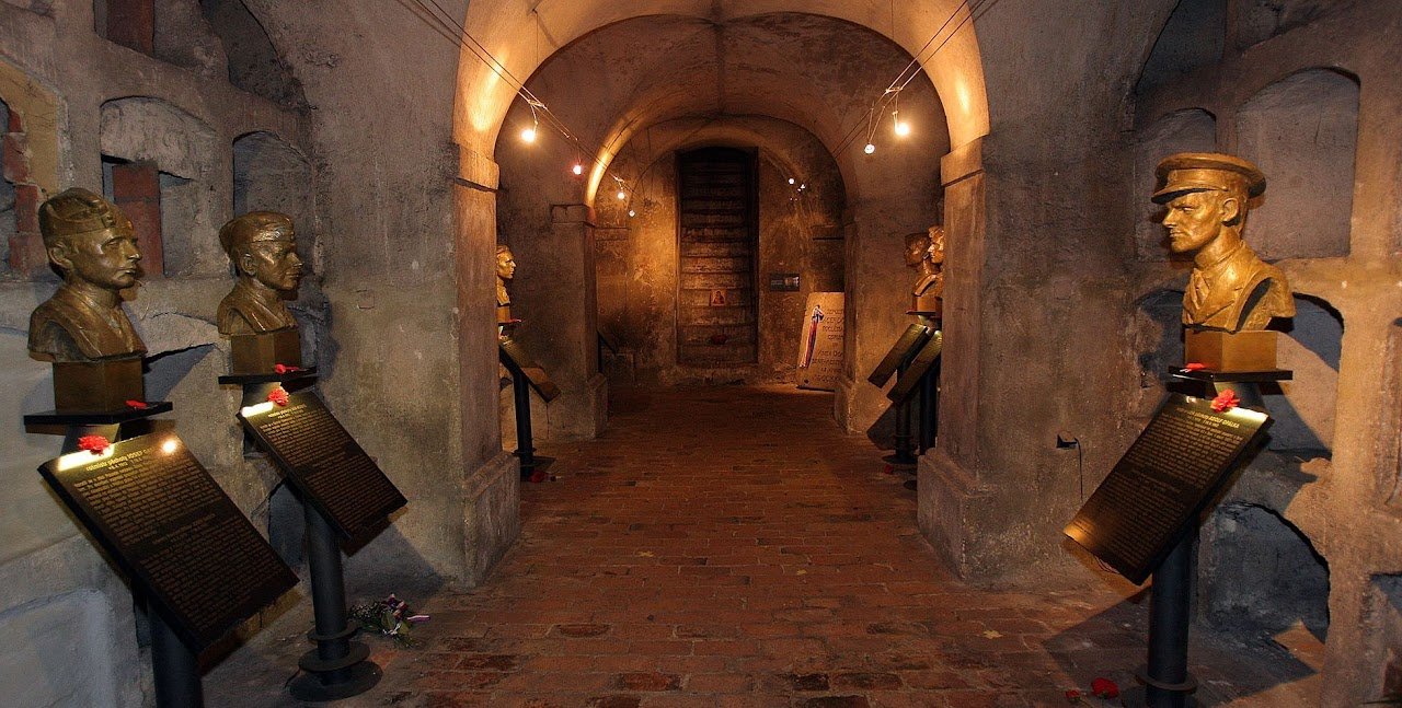 A brick walkway on either side of the bronze busts placed on inclined commemorative plaques.